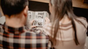 A couple reminisces while looking through a family photo album, capturing warm memories indoors.