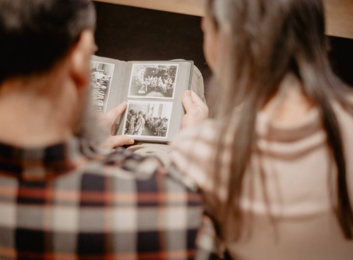 A couple reminisces while looking through a family photo album, capturing warm memories indoors.