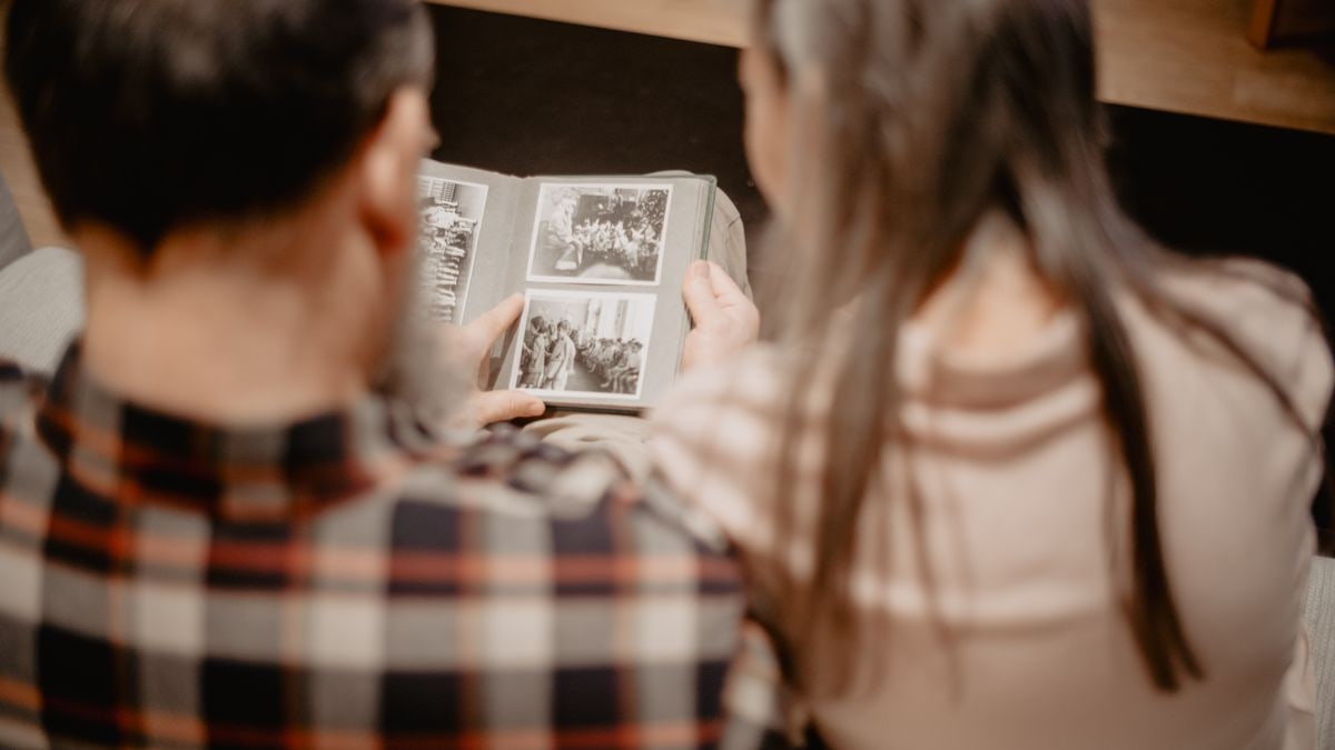A couple reminisces while looking through a family photo album, capturing warm memories indoors.